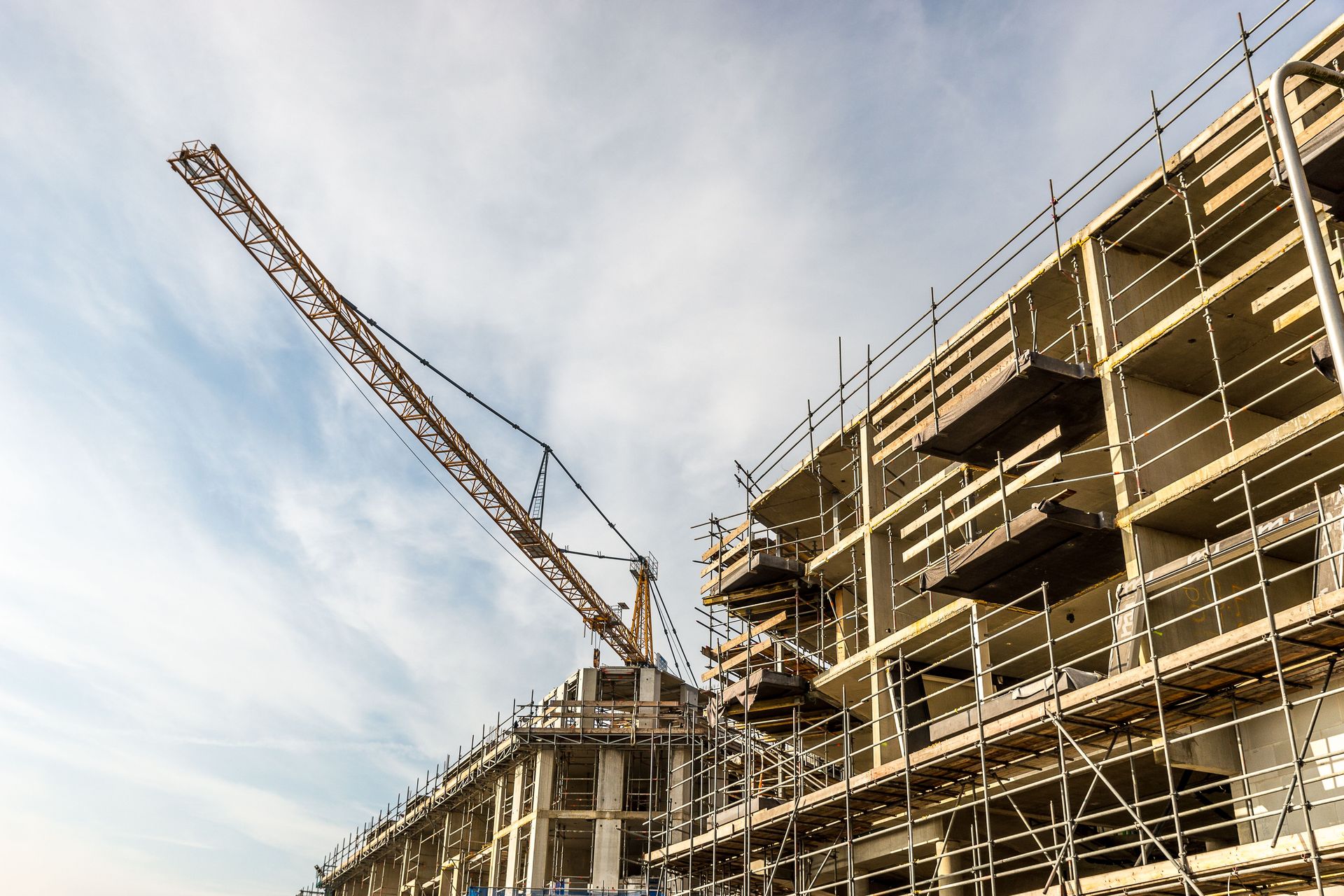 A dynamic view of a construction site with crane and scaffolding on a sunny day.